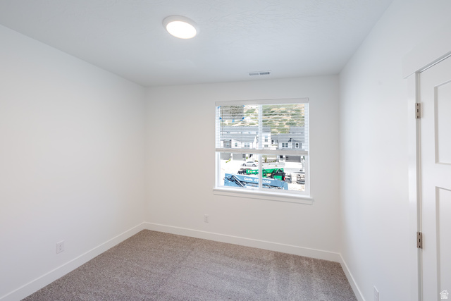 Neutral wall paint, recessed ceiling lighting, window with blinds, panel door, and carpet flooring