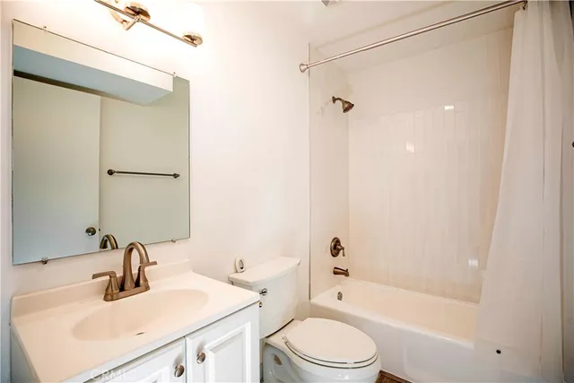 a bathroom with a bathtub shower sink vanity mirror and toilet