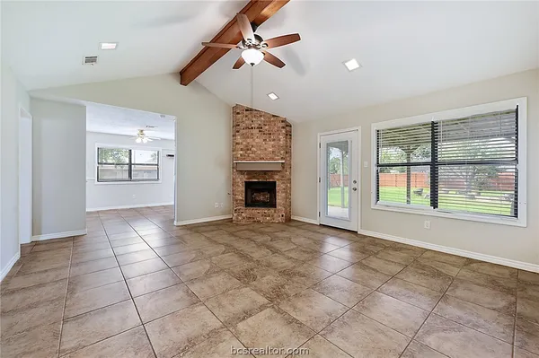 a view of an empty room with window and fireplace