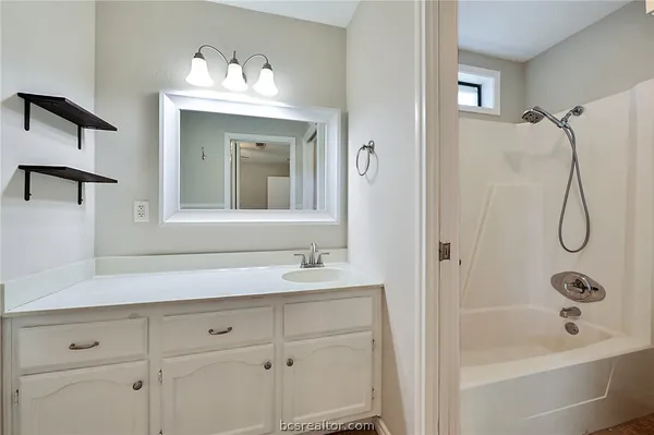 a bathroom with a bathtub shower sink vanity and mirror