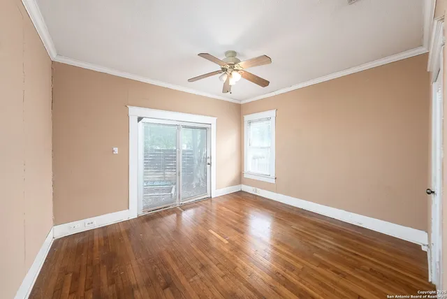 an empty room with wooden floor ceiling fan and windows
