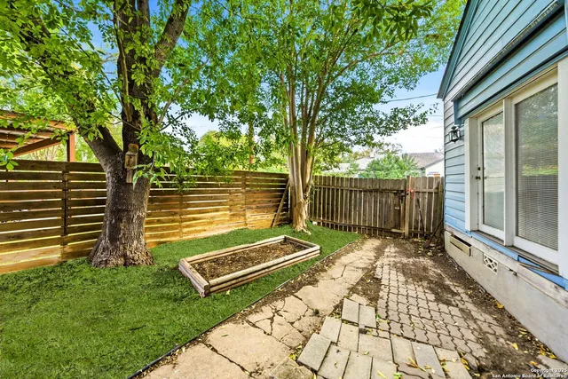 a view of a backyard with wooden fence and a large tree