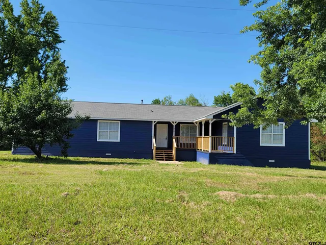 a front view of house with yard and trees in the background