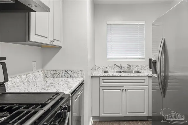 a kitchen with granite countertop a sink stove and cabinets