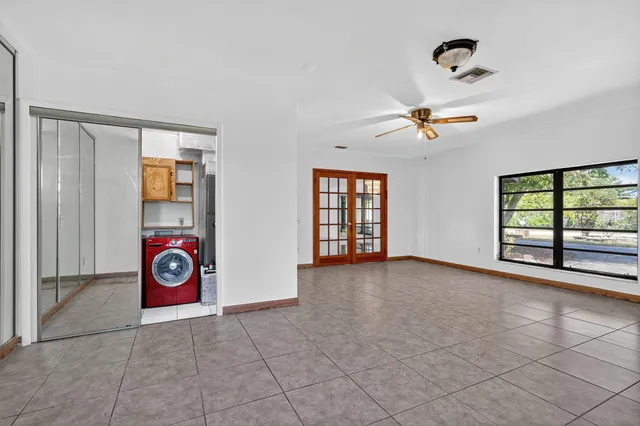 a view of an empty room with window and chandelier fan