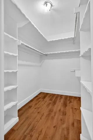 a view of an empty room with wooden floor and closet