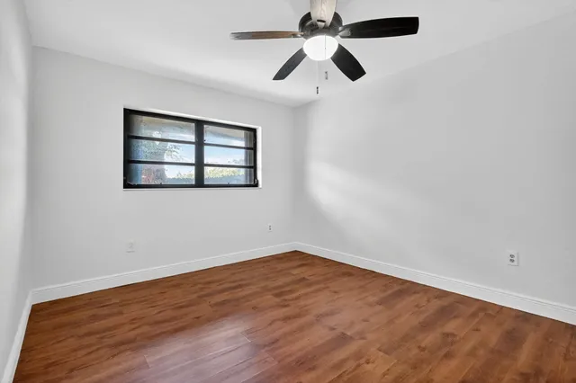 an empty room with a window and a fan