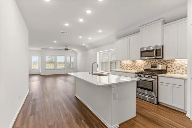a kitchen with stainless steel appliances granite countertop a sink stove and refrigerator