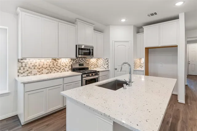 a kitchen with appliances a sink and cabinets