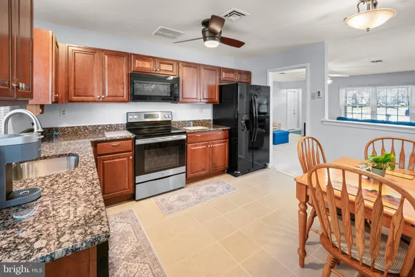 a kitchen with stainless steel appliances granite countertop a stove top oven a sink dishwasher a dining table and chairs with wooden floor