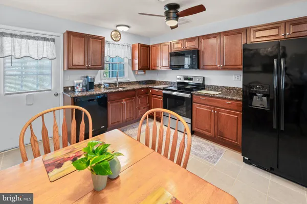a kitchen with stainless steel appliances granite countertop a refrigerator a stove top oven a sink dishwasher and wooden cabinets