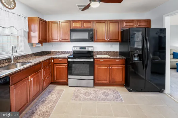 a kitchen with stainless steel appliances granite countertop a stove a refrigerator and a sink
