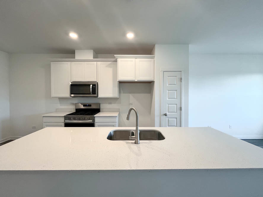 2108 Bodega Drive Oswego, IL 60543 - Photo 10 of 36 a kitchen with stainless steel appliances a sink a microwave a refrigerator and cabinets