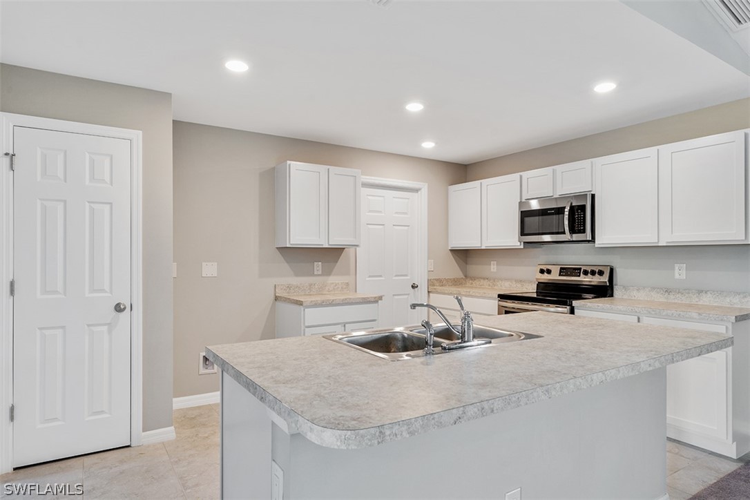 2819 37th Street Southwest Lehigh Acres, FL 33976 - Photo 3 of 14 a kitchen with sink a stove and cabinets