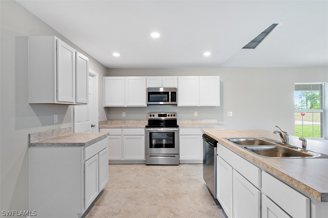2819 37th Street Southwest Lehigh Acres, FL 33976 - Photo 4 of 14 a kitchen with stainless steel appliances granite countertop a sink stove oven and white cabinets