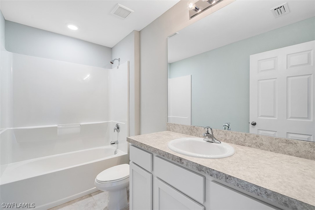 2819 37th Street Southwest Lehigh Acres, FL 33976 - Photo 9 of 14 a bathroom with a granite countertop sink a toilet and bathtub