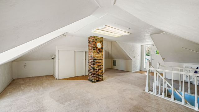 44 Shriver Street Eureka, UT 84628 - Photo 19 of 43 Expansive attic space featuring sloped ceilings, a brick column, recessed storage with sliding doors, a built-in stair railing, and an overhead fluorescent light fixture