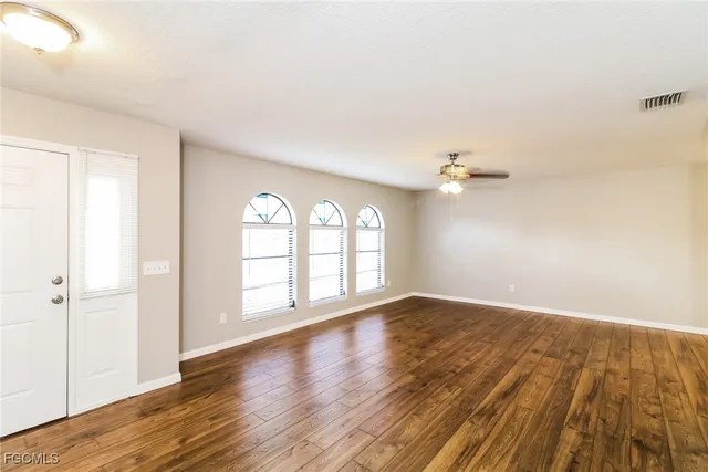 an empty room with wooden floor and windows