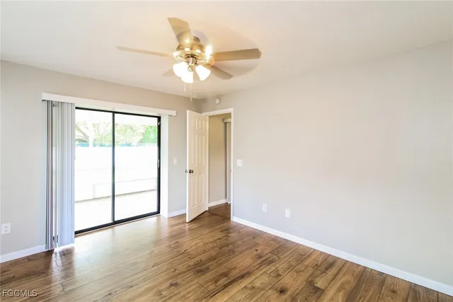 an empty room with wooden floor fan and windows