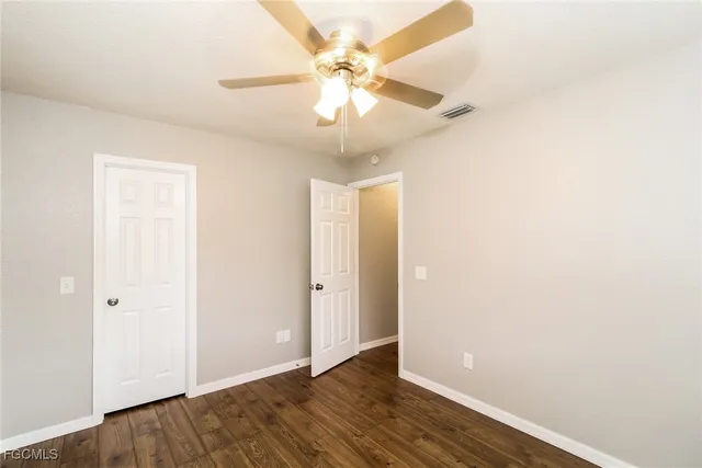 an empty room with wooden floor and fan