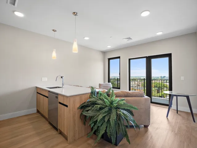 a living room with stainless steel appliances granite countertop furniture a sink a large window and wooden floor