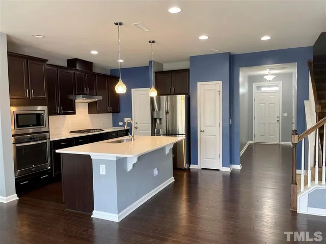 a large kitchen with stainless steel appliances kitchen island granite countertop a large counter top and a stove