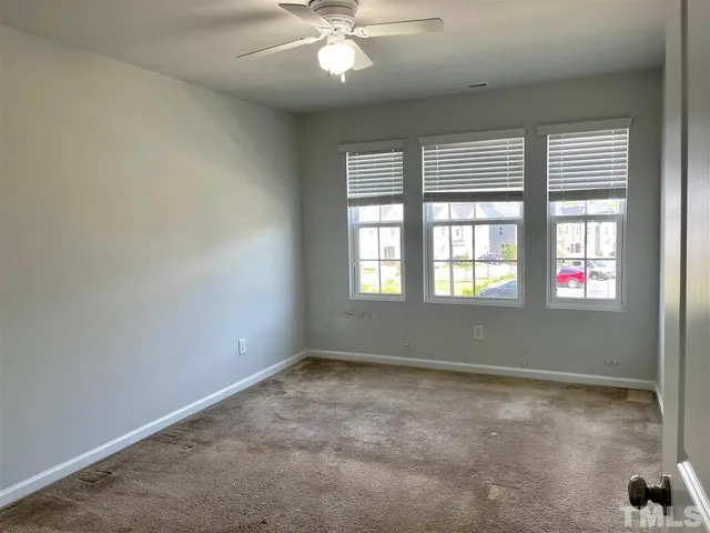 an empty room with windows and fan