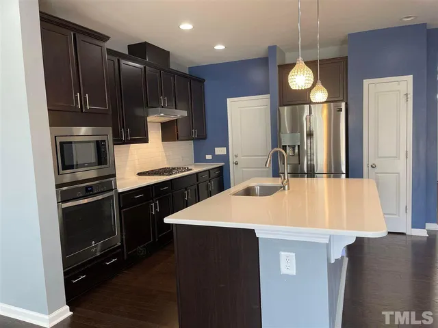 a kitchen with kitchen island wooden cabinets a refrigerator and a sink