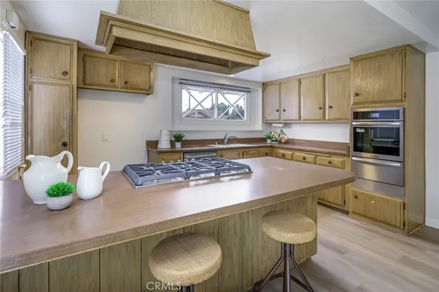 a kitchen with kitchen island granite countertop a sink chairs and cabinets