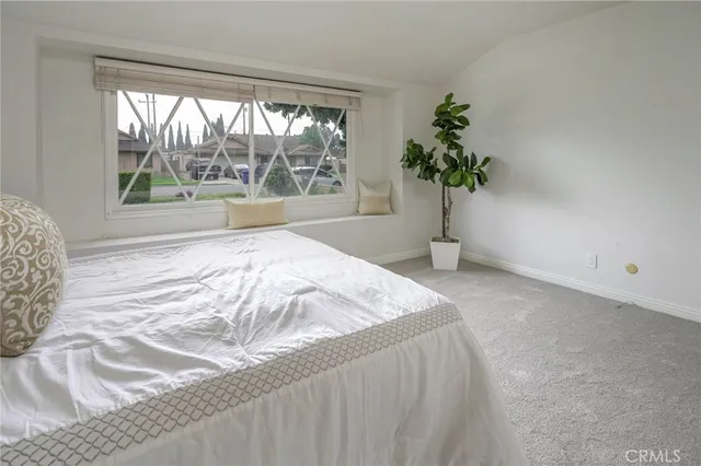 a bed sitting in a spacious bedroom next to a window