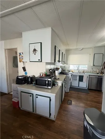 a kitchen with stainless steel appliances a sink and wooden floors