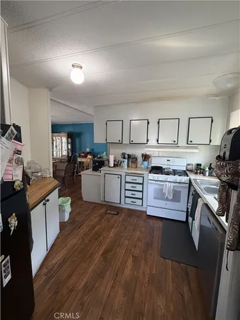 a kitchen with stainless steel appliances a stove a sink a refrigerator white cabinets and wooden floor