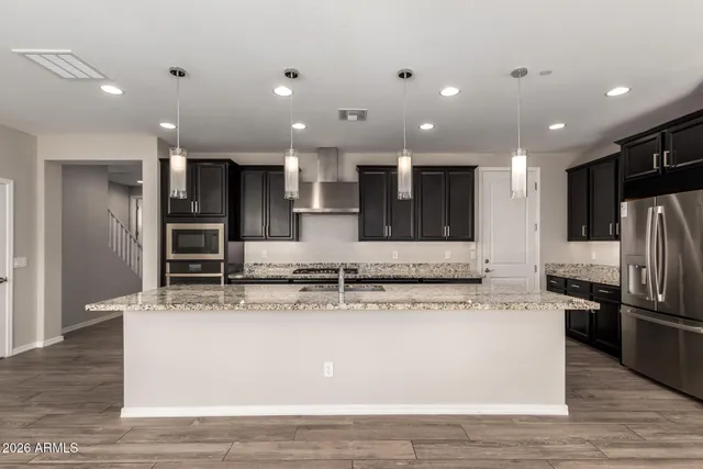 a large kitchen with stainless steel appliances kitchen island a large counter top and a refrigerator