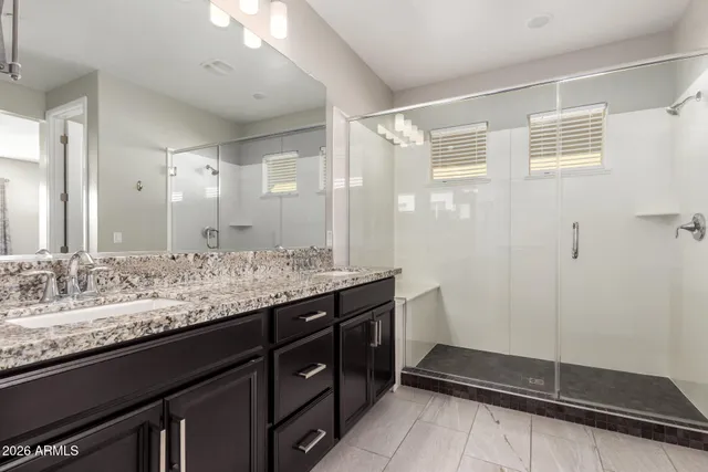 a bathroom with a granite countertop sink a mirror and a shower