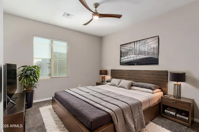 a bedroom with a bed a potted plant on a dresser and a window