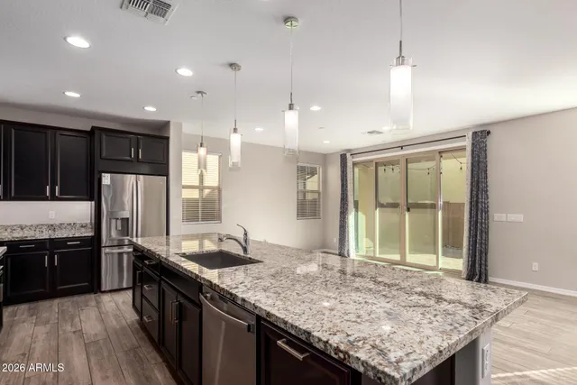 a kitchen with stainless steel appliances granite countertop plenty wooden cabinets counter space a sink and wooden floor