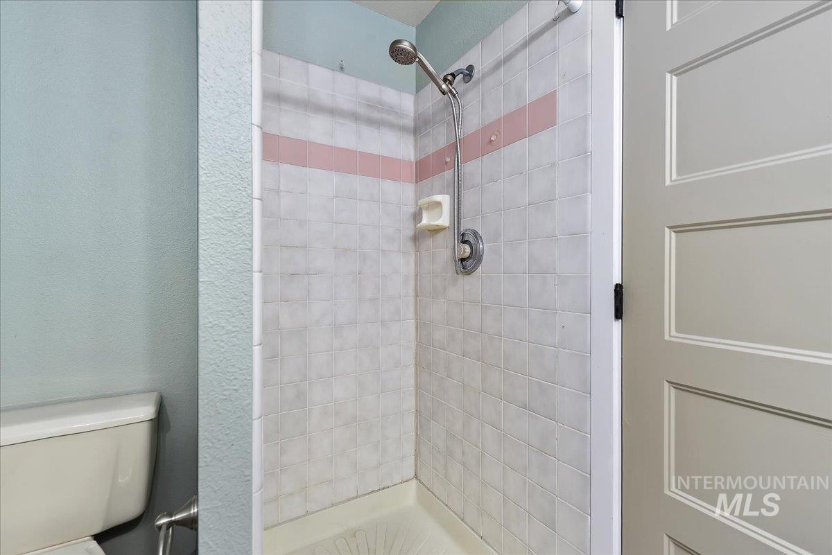 9215 West Preece Street Boise, ID 83704 - Photo 15 of 22 Shower stall with white square tiles and a horizontal pink accent band
