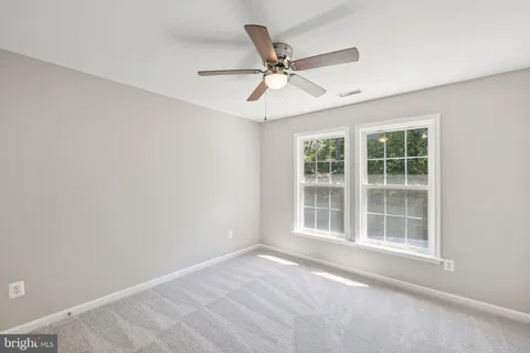 an empty room with window and ceiling fan