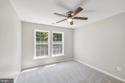 an empty room with window and ceiling fan