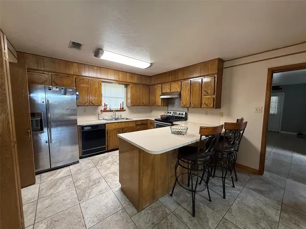 a kitchen with stainless steel appliances granite countertop a sink a stove a refrigerator and island