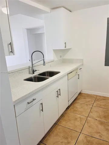 a kitchen with white cabinets and sink