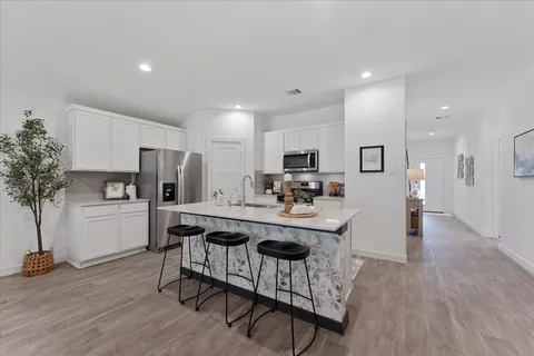 a kitchen with stainless steel appliances a dining table chairs microwave and sink