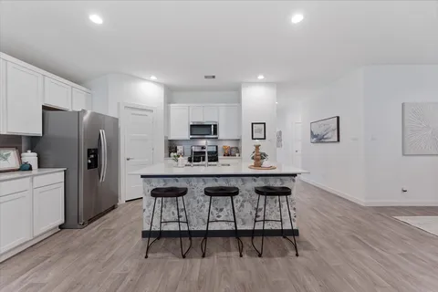 a kitchen with stainless steel appliances a table chairs refrigerator and wooden cabinets