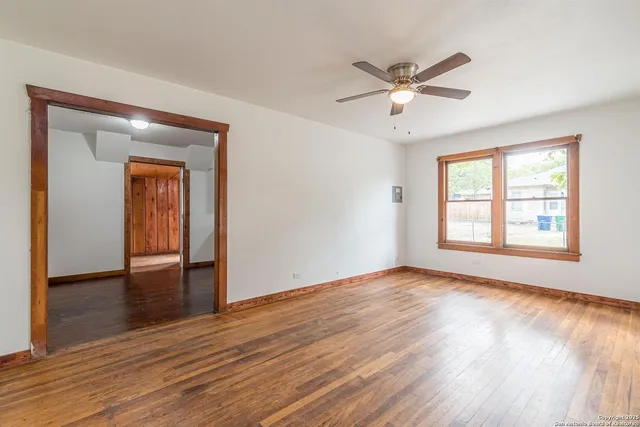 a view of an empty room with wooden floor and a window