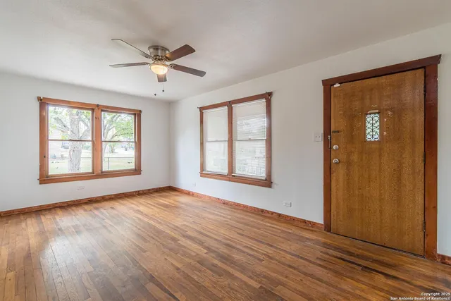 a view of an empty room with wooden floor and a window