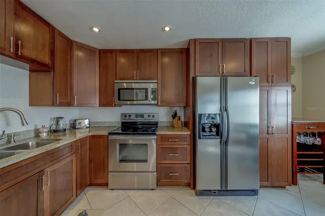 a kitchen with stainless steel appliances granite countertop a refrigerator and a stove top oven