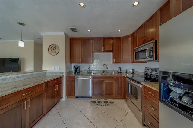 a kitchen with stainless steel appliances granite countertop wooden cabinets a stove top oven a sink and dishwasher