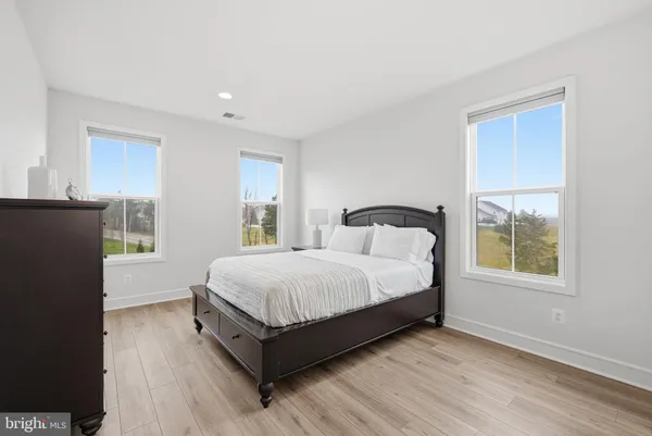 a spacious bedroom with a bed and wooden floor