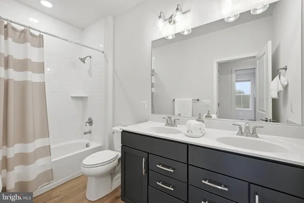 a bathroom with a double vanity sink toilet mirror and shower