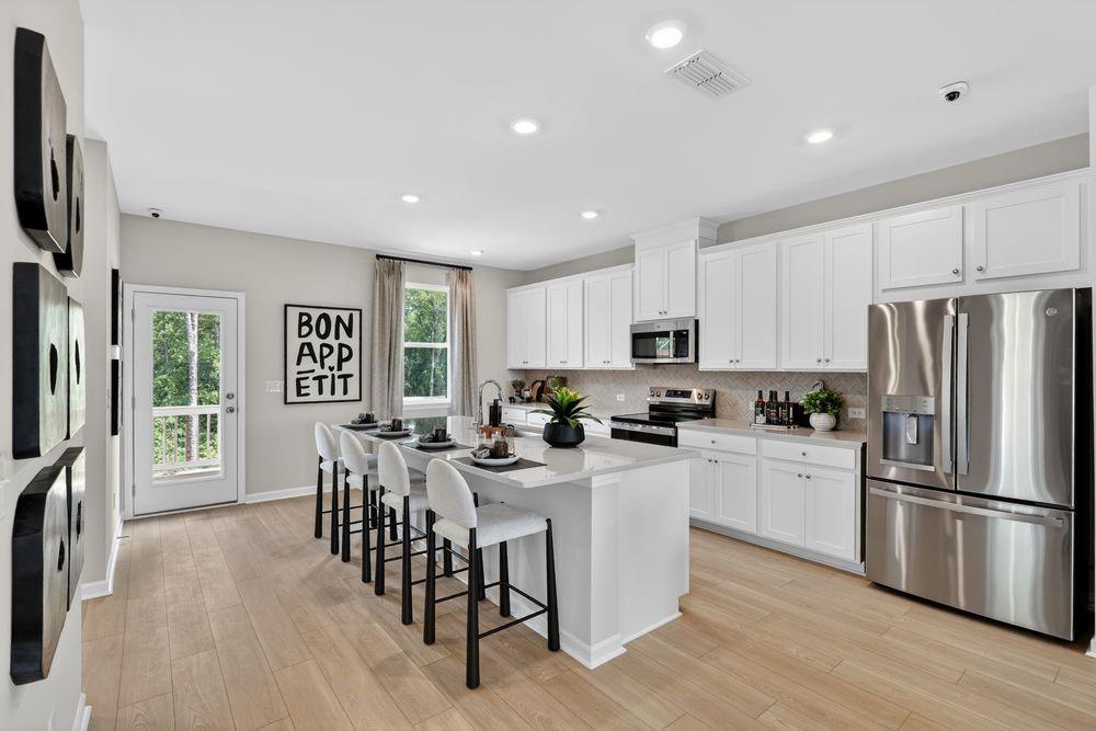 747 Meadow Ridge Lane Cumming, GA 30040 - Photo 10 of 41 a kitchen with stainless steel appliances a dining table chairs refrigerator and microwave